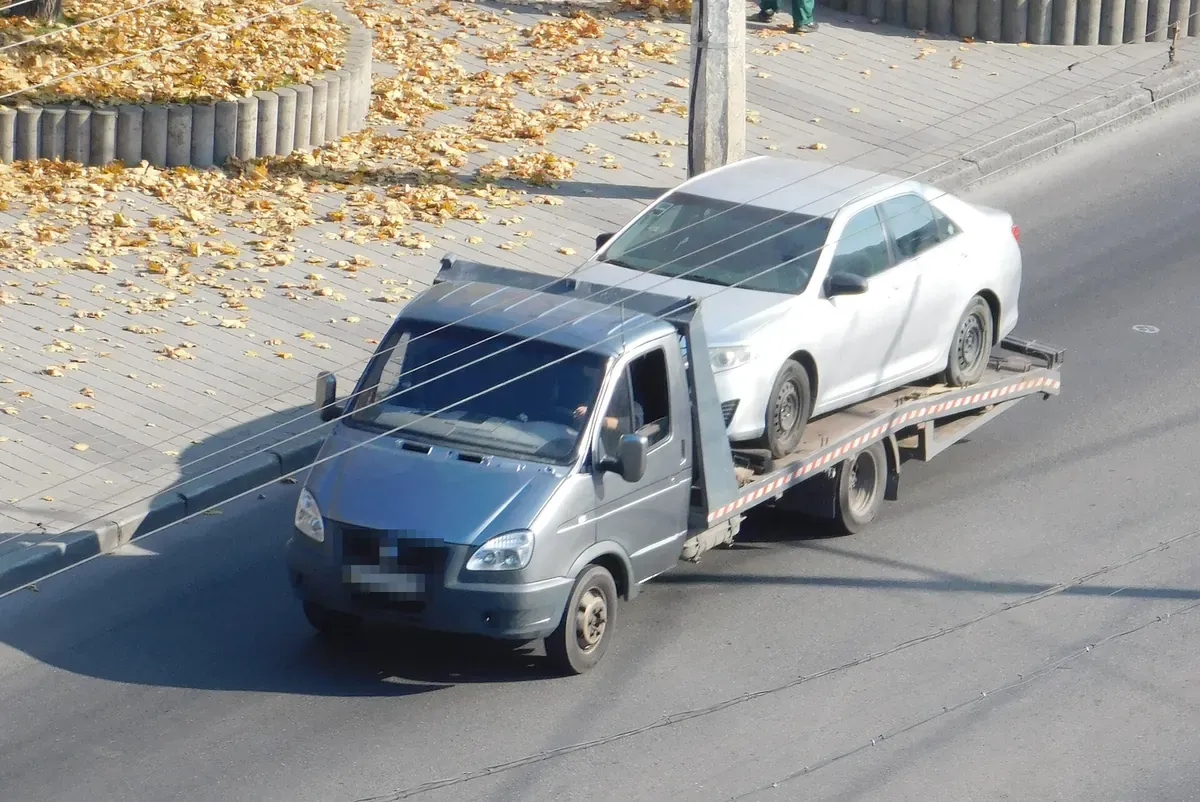 Kasasında otomobil taşıyan hafif çekici yolda